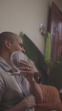 Sweating person using small portable fan