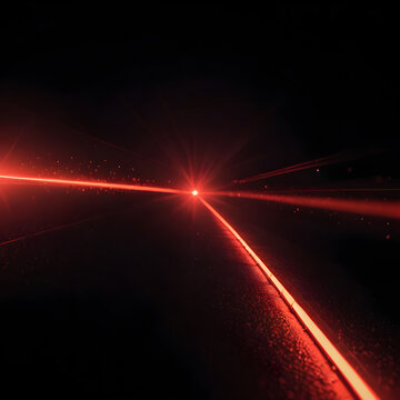Laser beam of bright red light cuts through darkness, reflecting on a textured surface.