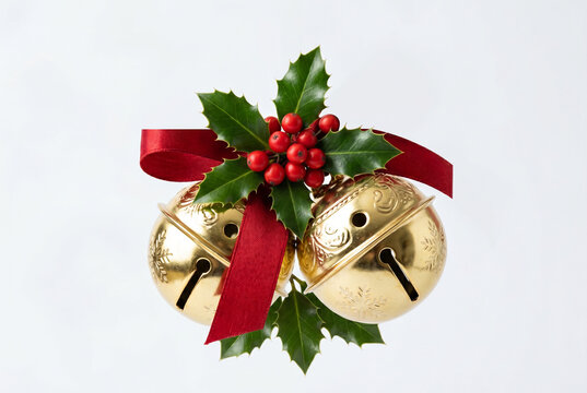 Golden christmas bells decoration with ribbon and holly over white joy isolated