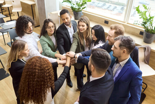 Business team people join hands showing unity. Diverse colleagues form a circle for teamwork and collaboration, symbolizing support, partnership and success. Strong concept of unity and teamwork.
