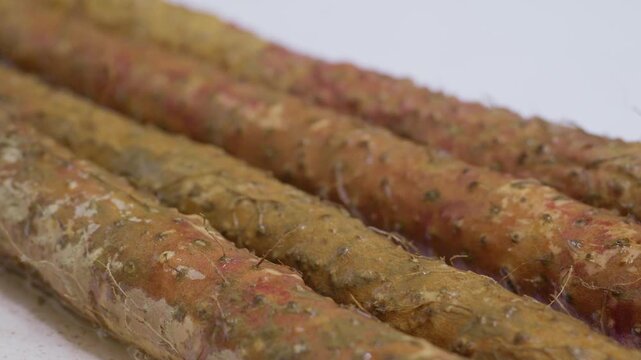 Extreme close-up shot of washing dirt off Chinese yam under running water.