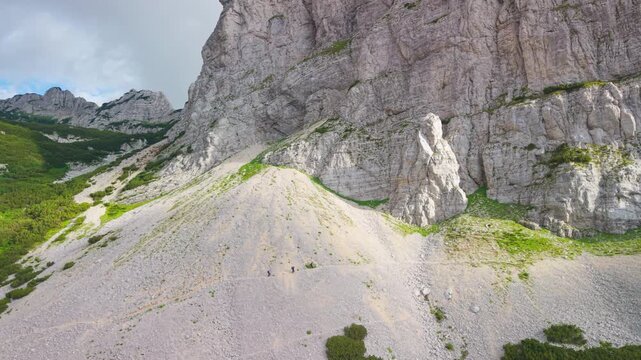 Hikers traversing a scree path along massive limestone cliffs on the approach to Skrcko Lake, Durmitor National Park, Montenegro