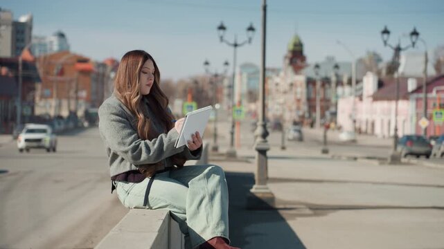 Pretty white woman illustrating fashion sketches on bench urban boulevard with landmark buildings, soft sunlight and long shadows, pencil on paper, elegant pose, thoughtful expression, aesthetic