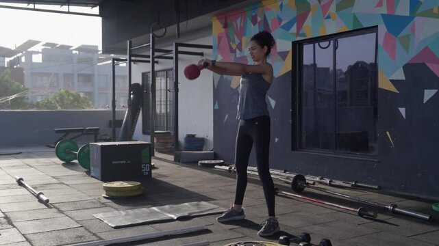 South Asian female athlete performs two handed kettlebell swings during a functional fitness workout in a modern indoor gym. Collection: WORKOUTSERIES2026.
