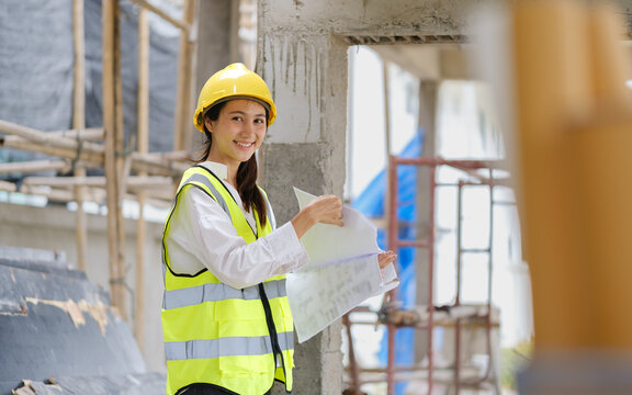Female construction engineer reviewing documents while inspecting an unfinished building.