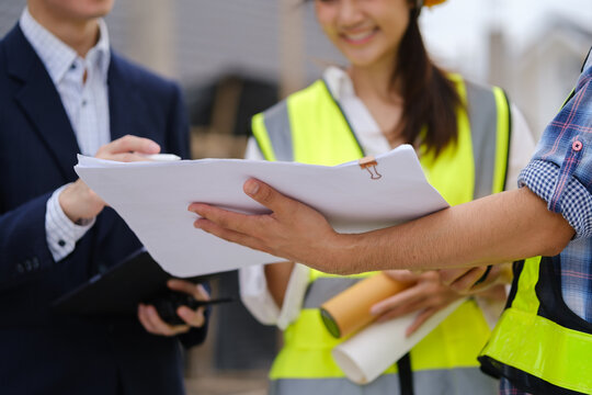Architects and engineers reviewing blueprints and a scale model at a construction site.