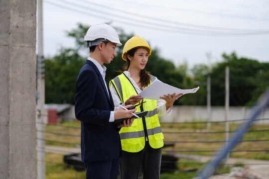Architects, engineers and a manager discussing blueprints during a site inspection.