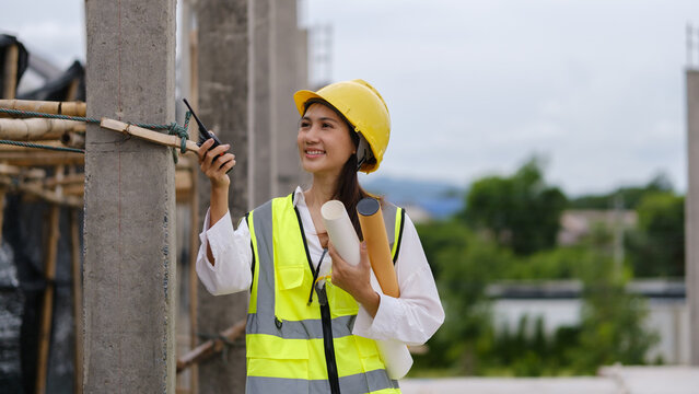 Female construction engineer making a phone call during a building site inspection.