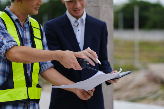 Architects and engineers reviewing blueprints and a scale model at a construction site.