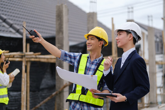Construction professionals using a two-way radio during a building site inspection.