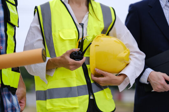 Construction professionals using a two-way radio during a building site inspection.
