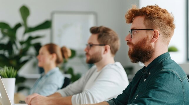 A group of diverse colleagues are seated at a desk attentively participating in a meeting or collaborative session in a bright contemporary business workspace