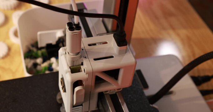 Close-up of a 3d printer head and cables on a desktop machine