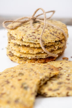Homemade pastry. Organic food. Savory cookies baked with seeds served on white plate. Healthy crispbread pile tied with rope background.