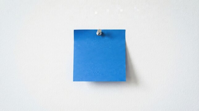 Blue sticky note pinned to a clean white wall for office task organization
