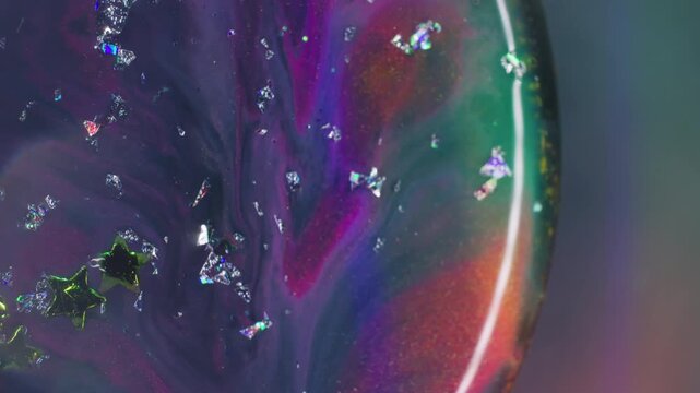 Colorful paint. Light stars texture. Defocused purple blue yellow golden crystal liquid floating on abstract neon bokeh background.