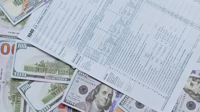Tax form is placed over background of US hundred-dollar bills