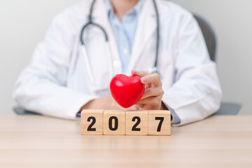 Fototapeta premium Happy New Year 2027 with Stethoscope of doctor and heart shape on table. health care, Insurance, Wellness and medical concepts