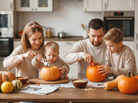 Cheerful family carving pumpkins at kitchen island