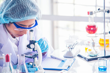 Fototapeta premium Chemistry Medical. Woman scientist in lab look at science microscope medical test researching biology chemistry in blue light black background. Female technician laboratory analyze genetic research