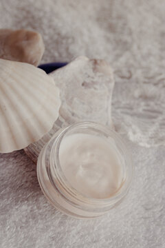 Skincare product and seashells on a white towel, symbolizing natural beauty, spa treatment, wellness, and cosmetic care with organic ingredients for healthy skin