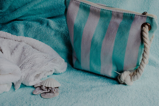 Beach bag and white towel on a soft blue background creating a relaxing scene, symbolizing self care, wellness, and a tranquil spa experience for personal beauty and calm