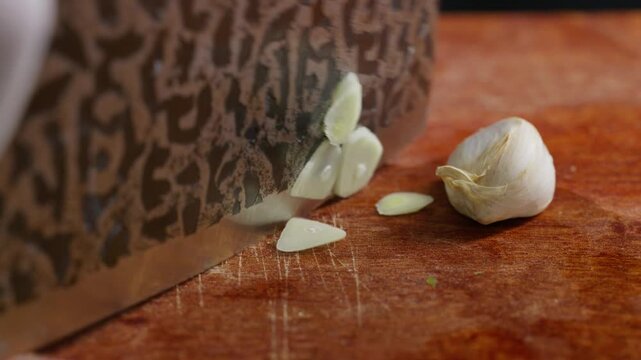 Macro extreme close-up shot of garlic being sliced into thin flakes.