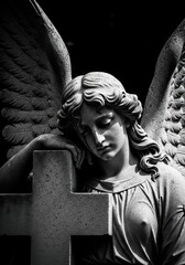 Fototapeta premium Mourning Angel Statue Leaning on a Cross in Black and White Dramatic Lighting for Cemetery Memorial
