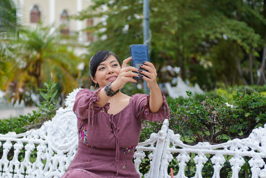 Cheerful Woman in Purple Dress Taking Selfie With Smartphone in Green Park