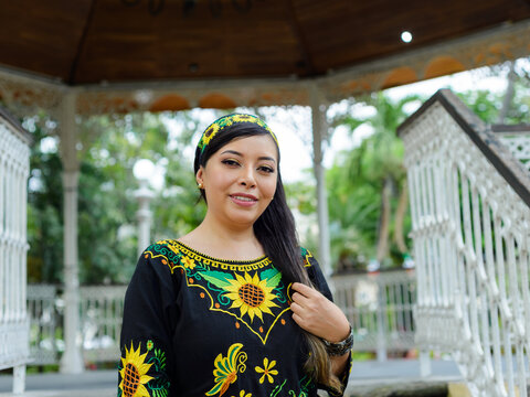 Confident Woman in Floral Embroidered Dress Posing in Ornate White Gazebo