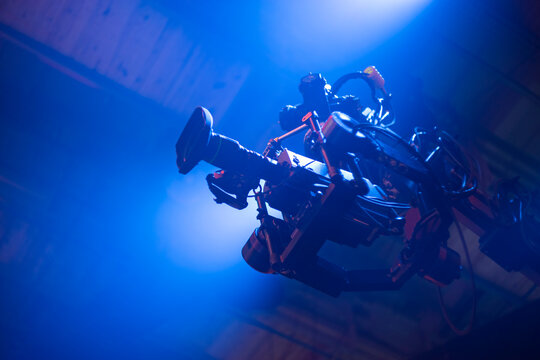 Professional movie camera on gimbal stabilizer rig with blue light copy space