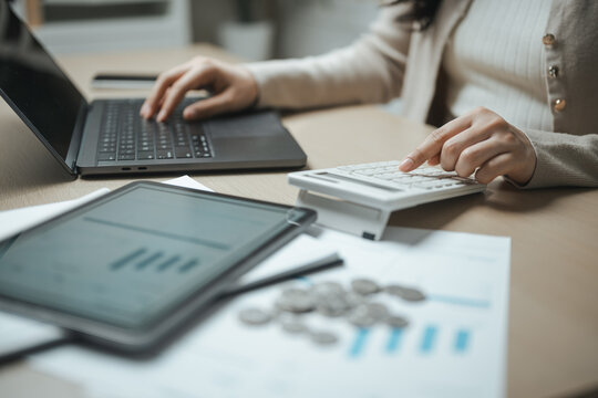 Business professional calculating financial data with reports, laptop and calculator for budgeting, investment analysis and corporate planning.