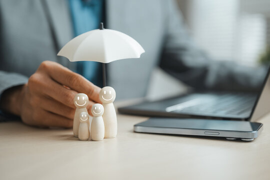 Wooden family figures under an umbrella symbolize health insurance, financial protection and long-term family security.
