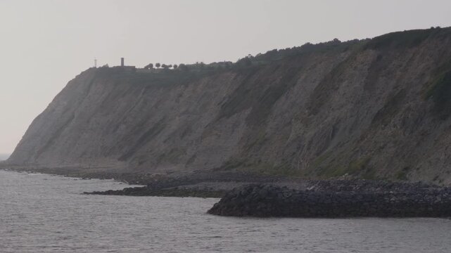 Observing dramatic coastal cliffs meeting the calm Cantabrian Sea, with rocky shoreline features and a distant lighthouse