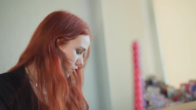 Medium shot caucasian redhead during focused scrying ritual, pink wand blurred in foreground, downward gaze and precise hand gestures, studio tabletop with props, soft natural lighting, intense