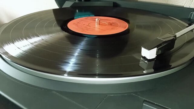 Vinyl record playing on black turntable with stylus arm