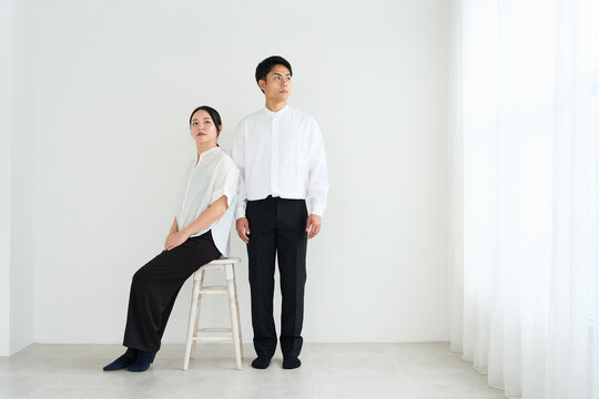 Young Japanese Man and Woman Standing Together Against White Wall
