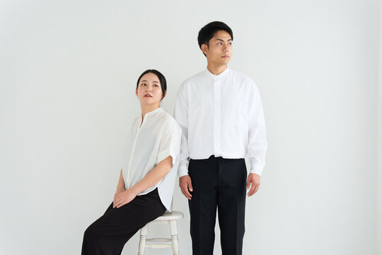 Young Japanese Man and Woman Standing Together Against White Wall