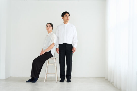 Young Japanese Man and Woman Standing Together Against White Wall