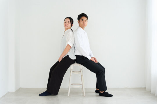 Young Japanese Man and Woman Standing Together Against White Wall
