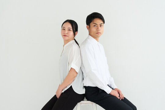 Young Japanese Man and Woman Standing Together Against White Wall