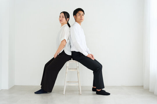 Young Japanese Man and Woman Standing Together Against White Wall