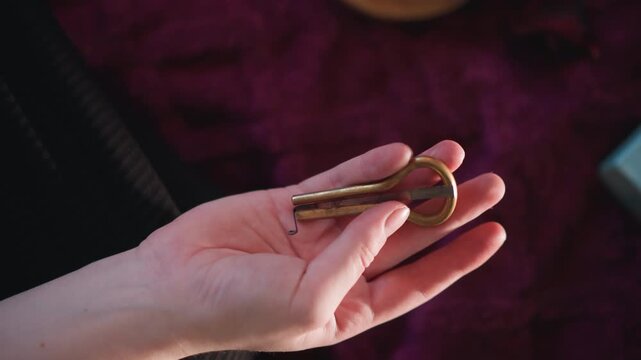 Caucasian hand holding antique key over burgundy velvet, closeup of brass skeleton key resting in palm, fingers gently turning key, fortuneteller mood with warm side light, intimate divination scene