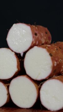 Vertical Video: Side profile close-up of a pile of fresh Chinese yams stacked together.