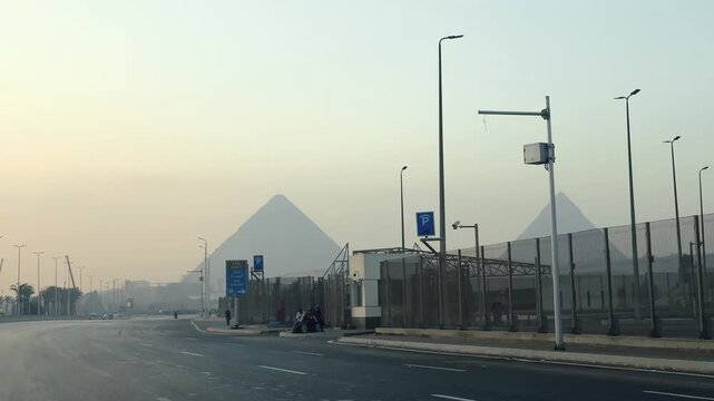 View from driving car of Giza Pyramids Rising above Urban Skyline Seen from El-Haram Street road in Cairo