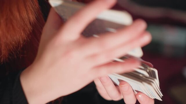 Fast deck shuffle. Performing swift riffle shuffle under dramatic lighting conditions with showmanship. Closeup of hands expertly executing rapid riffle shuffle with mystic and suspenseful energy
