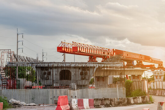 Image shows a construction site for a new concrete road and bridge, with large red steel beams and cranes at work a crucial infrastructure project for a major city.