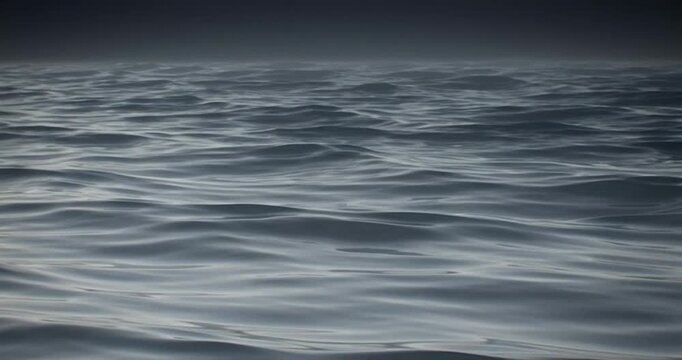 Dark ocean waves rolling rhythmically in this seamless loop animation showing the endless deep blue sea under a moody overcast sky in cinematic digital motion footage.