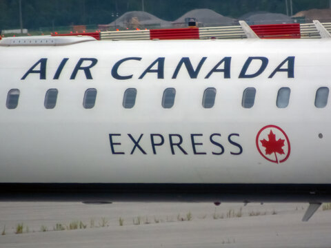 Calgary, Alberta, Canada. August 9, 2026. Close up view of Air Canada Express logo and maple leaf roundel on white airplane fuselage.