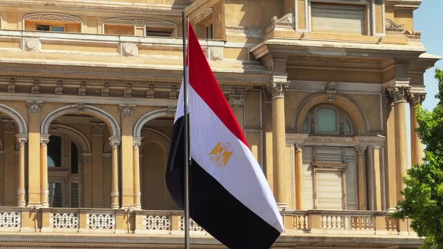 Egyptian National Flag waving near Neoclassical Historic Building Facade in Downtown Cairo